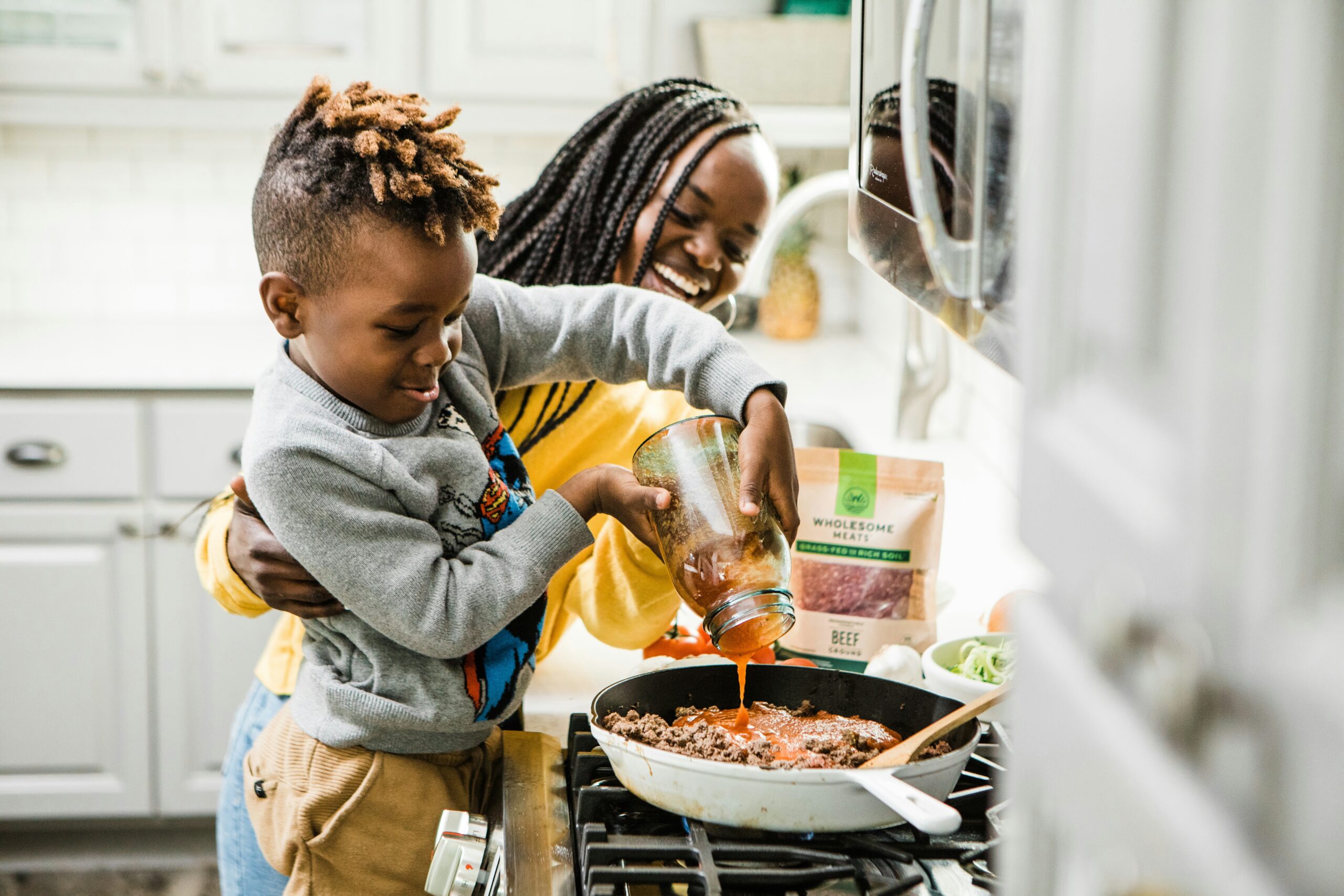 A mother and young boy cooking together at home.