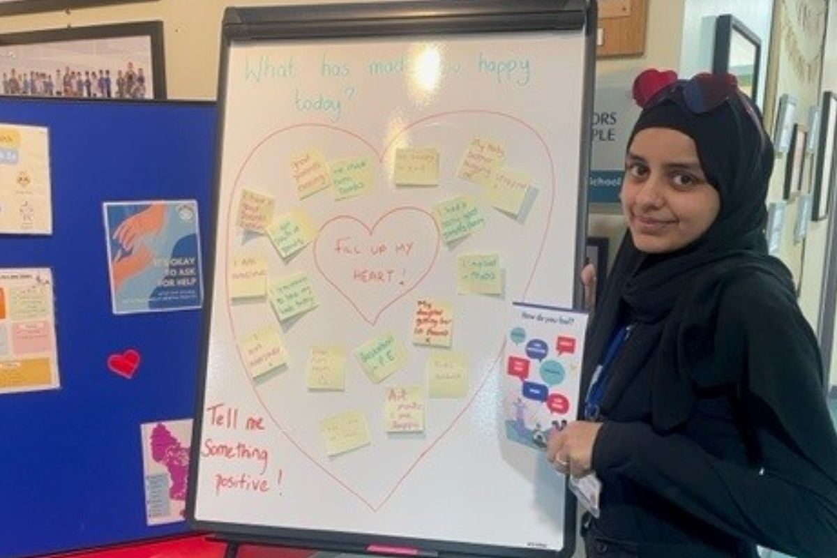 EMHP Anisah standing next to whiteboard filled with positive messages