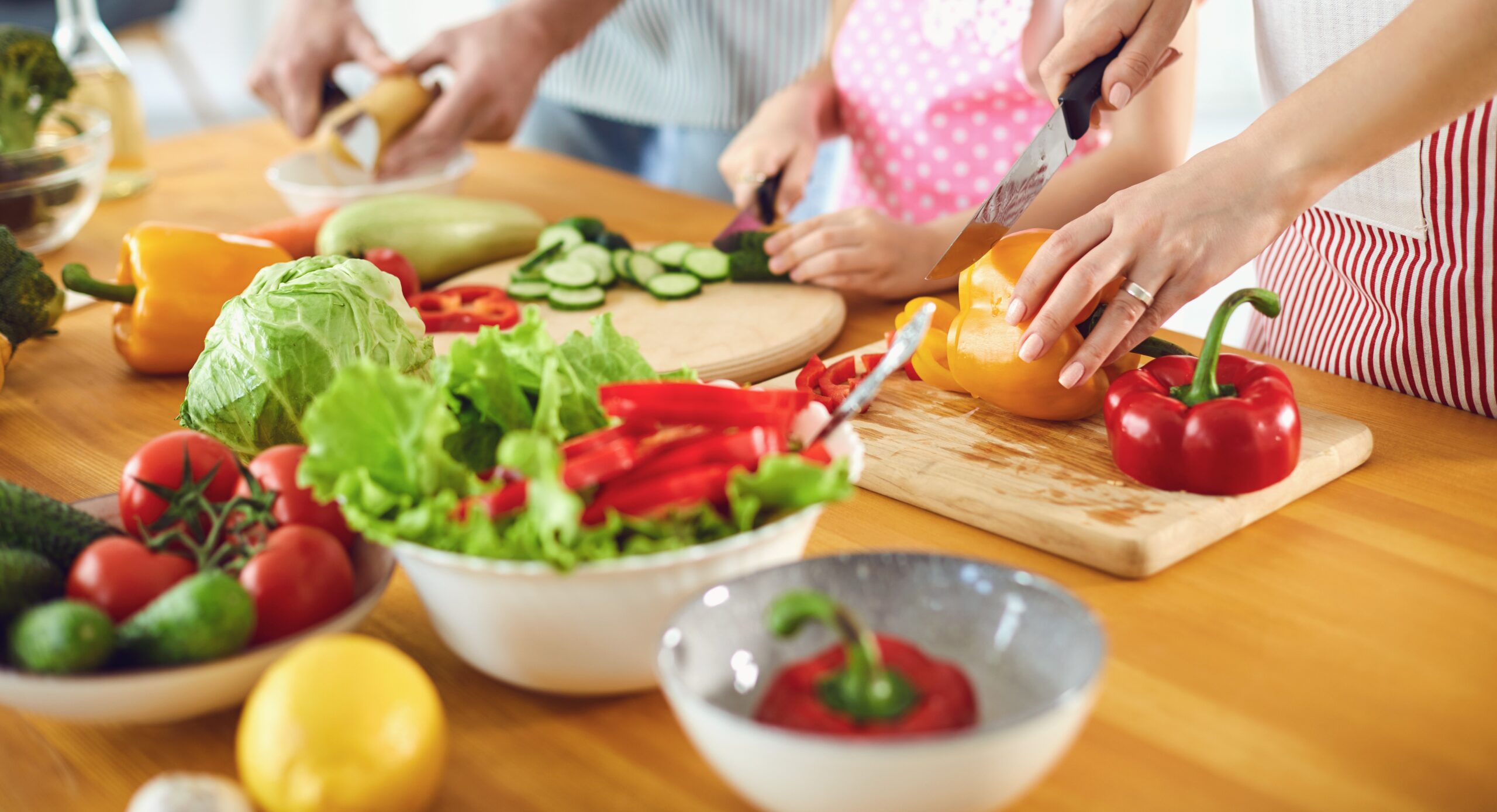 Brightly coloured fruit and vegetables being prepared on a worktop by young people. 