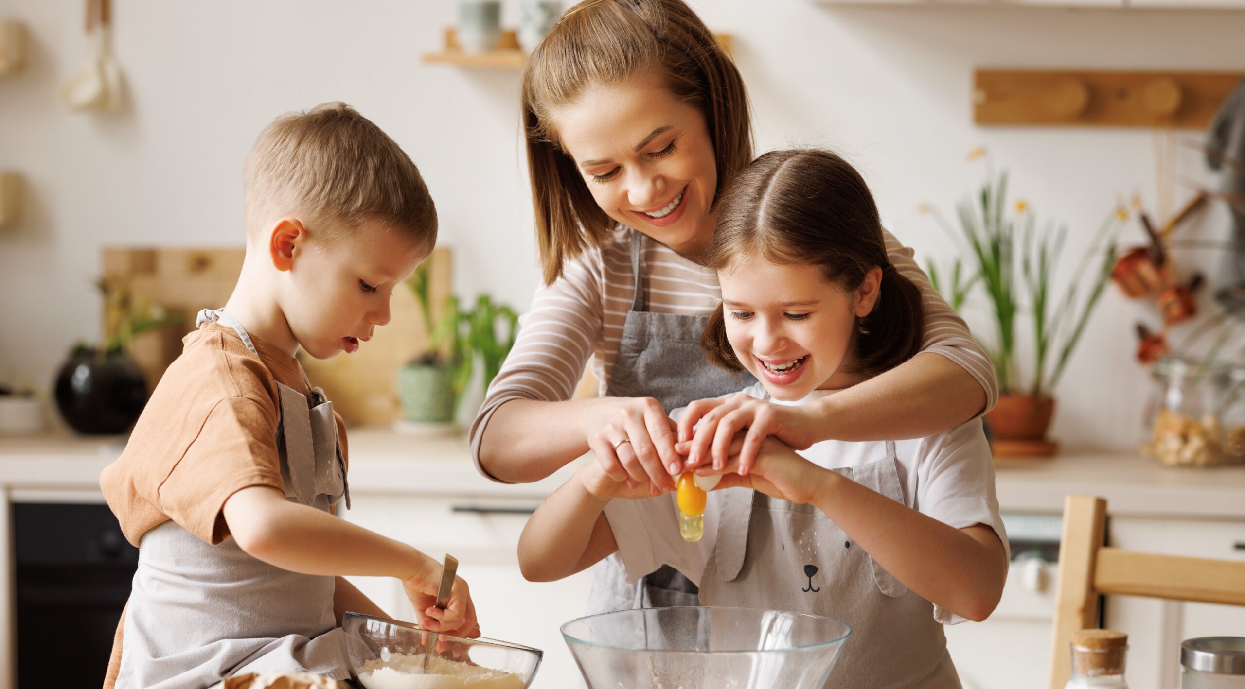 A woman teaching her daughter and son how to cook.